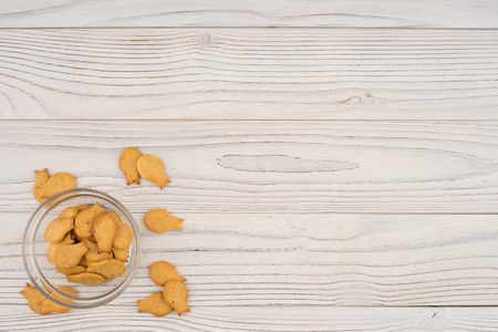 Goldfish cracker in a glass bowl on a white wooden table. Top view.の写真素材
