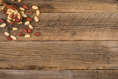 Peanuts in wooden spoons on an old wooden background. Top view.の写真素材