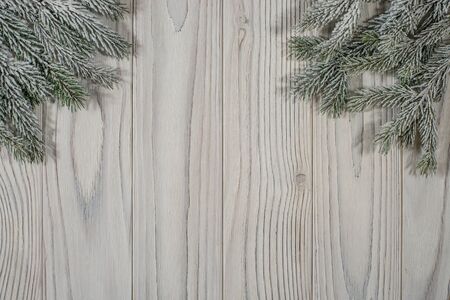 Spruce branches with snow on an old white wooden table. Top view.