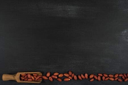 Peanuts in a scoop on a black chalkboard. Top view.の写真素材