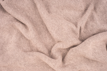 close up beige knitted pullover background. Top view.