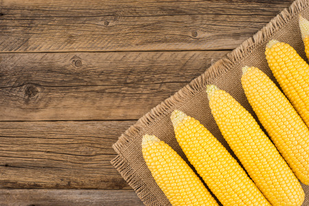 Ear of corn on an old wooden table. Top view.