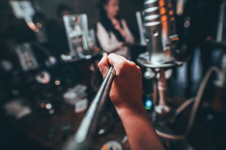 the girl smokes a hookah. Cable tube into the camera. from the first person. the background is indistinct. tightens smokeの写真素材
