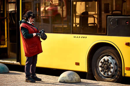 The conductor is nervous smoking near the empty bus and counting the money. there are no people. quarantine. empty city. street photoのeditorial素材