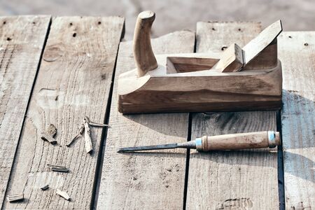 wooden background. Jointer plane and chisel with sawdust lie on the village table. working surface...