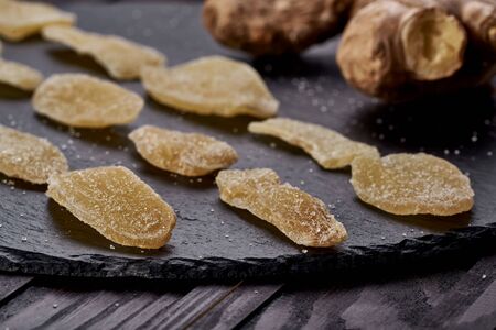 Ginger dried fruit slides spread beautifully on a black plate. side view. on a wooden table. Against viruses and diseases. immune productの写真素材