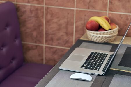 A laptop lies on a table next to a computer mouse. fruit in a vase. quarantine. covid-19. stay at home. work homeの写真素材