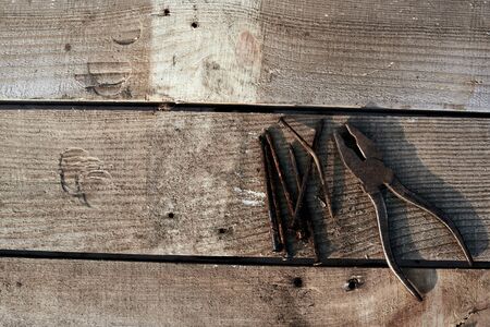 Rusty pliers and bent old nails lie on a tree desktop. rust. A cracked, scratched homemade table....