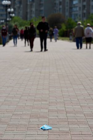 A medical mask lies on the sidewalk, on the asphalt. end of a quarantine. cancellation of a coronavirus. there is no pandemic. strike. People are tired of covid-19. soon finish.の写真素材