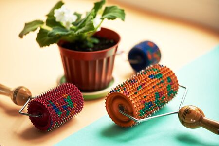 Three massager with red, orange and blue drums, metallic needles lie near a vason on a yellow-green surface. Subject and promotional photography. For relaxation and health.の写真素材