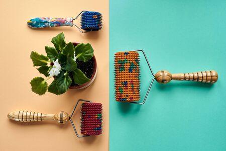 Three masseurs with red, orange and blue drums, metallic needles lie near a vason on a yellow-green surface. top view. Subject and promotional photography. For relaxation and health.の写真素材