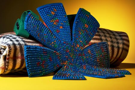 A blue massage mat in the form of chamomile lies on the plate in the cage on a yellow background....