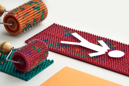White paper man lies on a massager, near there are rollers of two types on multicolored mats. top view. healthy lifestyle. Advertising, thematic and subject shooting. For relaxation and healthの写真素材