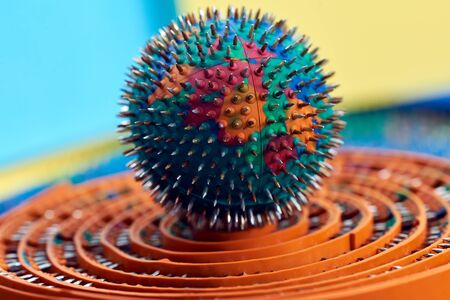 Green round hand massager with rubber and thorns, needles of metal, lies on orange surface. Advertising, thematic and subject shooting. For relaxation and healthの写真素材