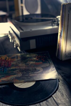 The vinyl disc lies on a table near the vinyl player, amplifier and acoustics. Old school turntable. art project. musical atmosphere. Old player and analog music. subject photo.の写真素材
