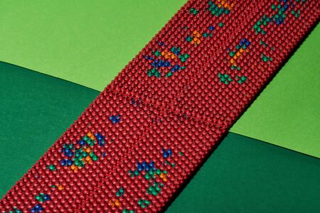 Masseur in the form of a red carpet with metal spikes, lying on green backgrounds, diagonal....