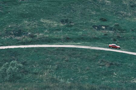 Nature and red car. Country landscape. Composite shot. The car on a green background. Grass, trees, fieldsの写真素材