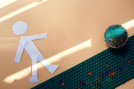 A white paper man plays football with a barbed massage ball on a green mat. top view. healthy lifestyle. Subject and promotional photography. For relaxation and health.の写真素材