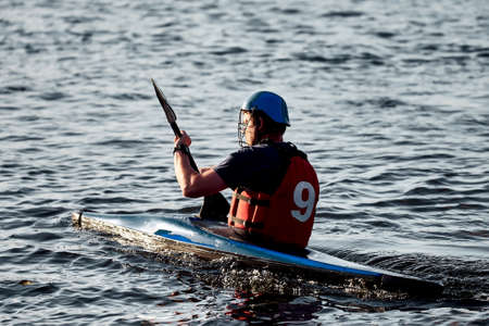 Kiev, Ukraine, 10.06.2020: A guy wearing a helmet on a canoe polo rowing a paddle and sailing on water. canupolo. puts on a rescue yellow. water splashes.のeditorial素材
