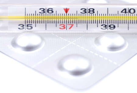 Thermometer and pills on white