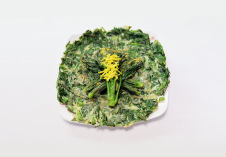 Thai style fried spinach with yellow flower in plate on white backgroundの写真素材