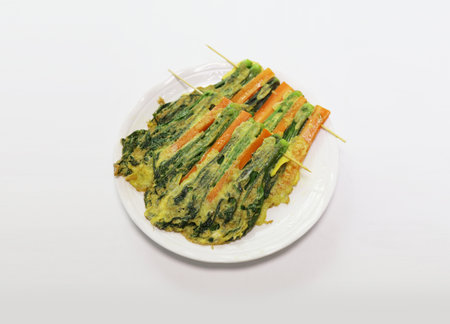 Spinach and carrot skewer on white plate on white backgroundの写真素材
