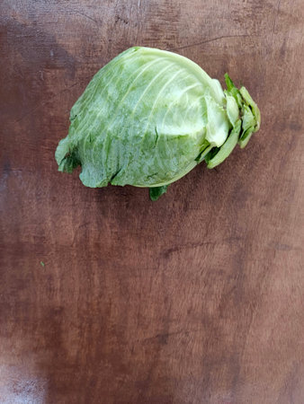 Top view of a fresh green cabbage on a rustic wooden background. Perfect for representing organic vegetables, healthy food, farm produce, and cooking ingredients. Suitable for useの写真素材