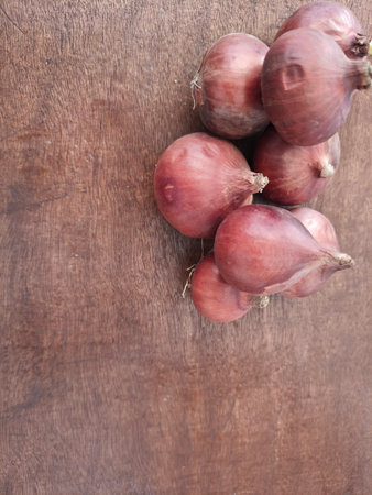 Close-up image of fresh organic red onions placed on a rustic wooden background. Perfect for illustrating healthy cooking, farm vegetables, kitchen ingredients, or natural food theの写真素材