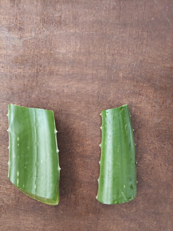 Close-up of two freshly cut Aloe Vera leaf slices placed on a rustic wooden surface. Natural herbal plant rich in vitamins and antioxidants, widely used in Ayurveda, skincare, andの写真素材
