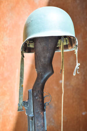 Military helmet supported on a firearm. Concept of unknown soldier.