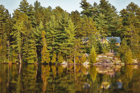 House in autumn forest landscape and reflection in the lake. La Mauricie National Park, Canada.の写真素材