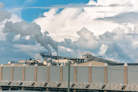 Concept of pollution. The smoke from the chimneys, mixes with the clouds in a blue sky. Canada.の写真素材