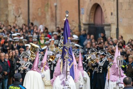 SALAMANCA, SPAIN - APRIL 18, 2019: Typical scene of the Spanish Holy Week, with religious dressing the typical Easter cap, music band numerous spectators and forces of order.のeditorial素材