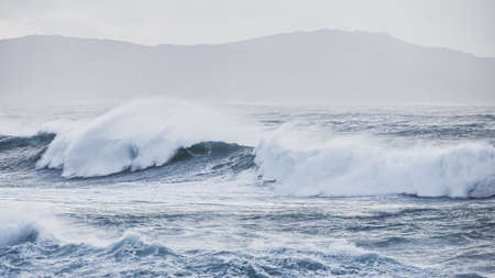 Big waves hit the rocks in rough seas. On a cloudy day. Galicia Spain.