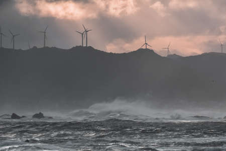 Big waves break on the coast, in the sunlit sea, passing through the clouds at sunset. Galicia,...