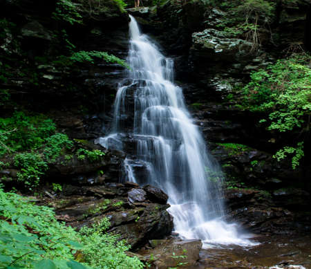large waterfall flowing over rocks in a forestの写真素材