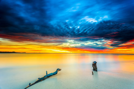 Beautiful sunset views all over the coast of the Mentawai Islands, West Sumatra, Indonesia. The waves are big for world-class surfers. White sandy beaches, boulders, and large cliffs, decorated with charming coconut trees, mangroves, and weathered tree trunks. Long exposure photoの写真素材