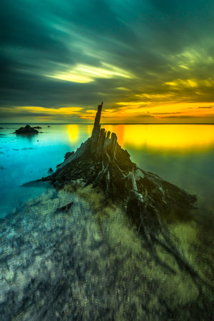 Beautiful sunset views all over the coast of the Mentawai Islands, West Sumatra, Indonesia. The waves are big for world-class surfers. White sandy beaches, boulders, and large cliffs, decorated with charming coconut trees, mangroves, and weathered tree trunks. Long exposure photoの写真素材