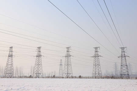 Stand high voltage towers in the snowy fields