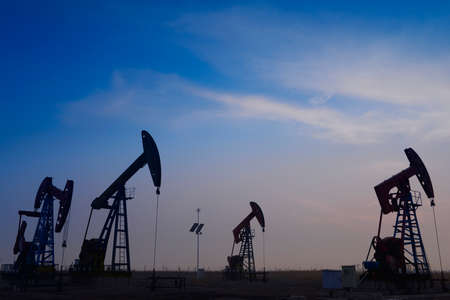 Many are operation of pumping unit in oil field in the eveningの写真素材