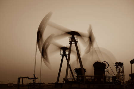 Is operation of pumping unit under the sunset of oilfield, close-upの写真素材