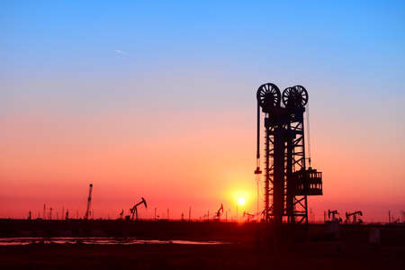 Working oil derrick in field under the setting sunの写真素材