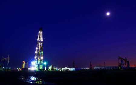 The oil derrick in work, in the oil field in the evening