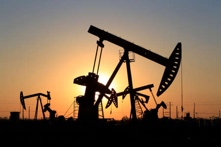 The pumping unit was working, silhouetted against the sunsetの写真素材