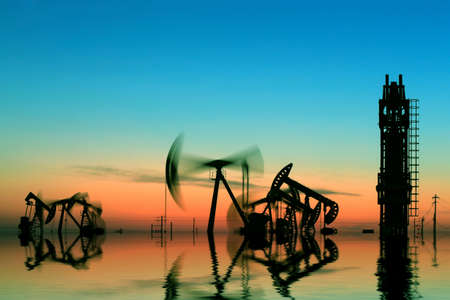 The pumping unit is working under setting sunの写真素材