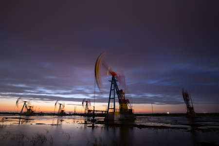 The pumping unit is working in the setting sunの写真素材