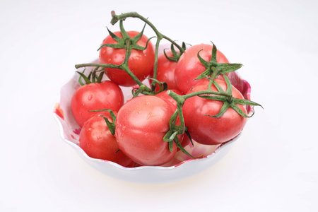 Tomatoes are in the basket, on the white backgroundの写真素材