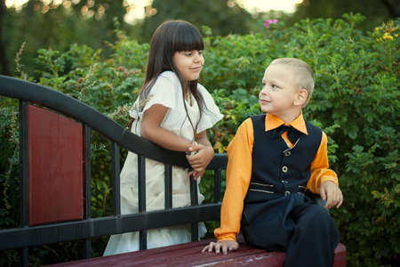 little boy and girl sitting on a bench,  boy and girl looking onの写真素材