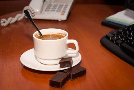 Cup photo on an office desk with a phone in the backgroundの写真素材