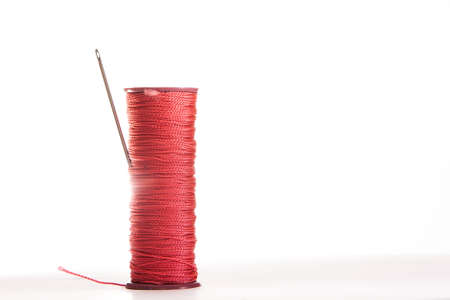 Spool of thread and needle on a white background